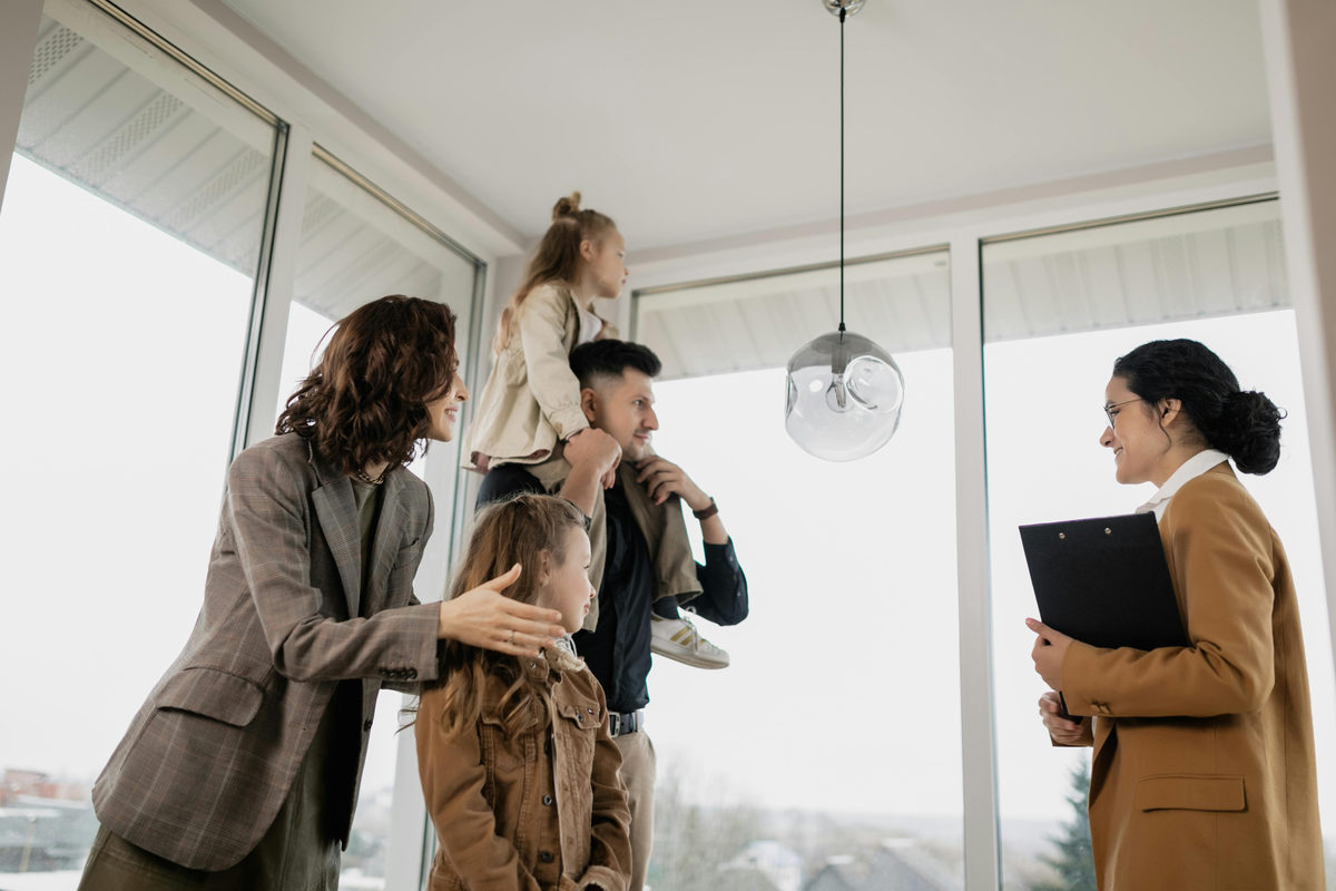 People viewing an empty room with a person holding a folder.