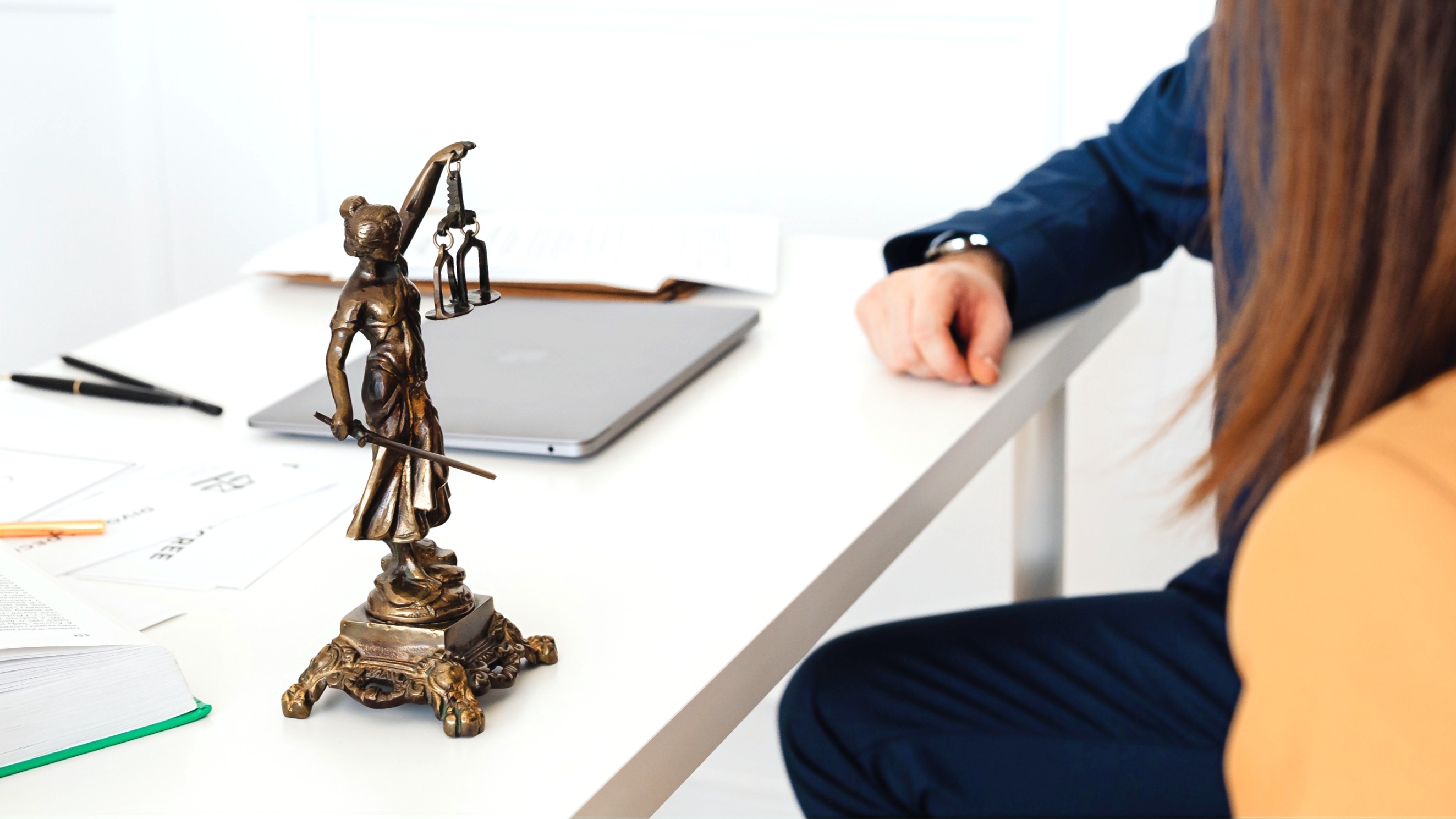 A justice figurine beside documents on a desk.